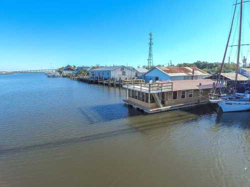 A calm waterway lined with colorful houses and a sailboat, under a clear blue sky.