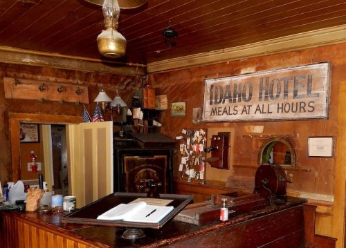 Interior of the Idaho Hotel, featuring a wooden reception desk, vintage decor, and a sign reading "Meals at All Hours."