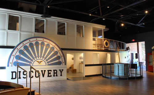 Interior of a museum exhibit featuring a large "Discovery" mural and modern architectural design.