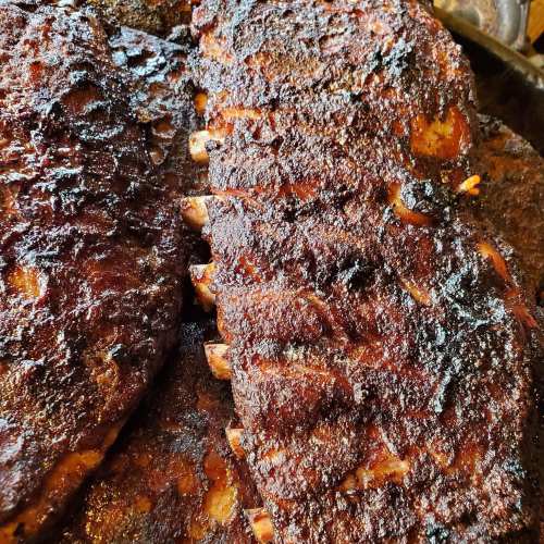 Close-up of perfectly cooked, smoky barbecue ribs with a dark, caramelized crust.