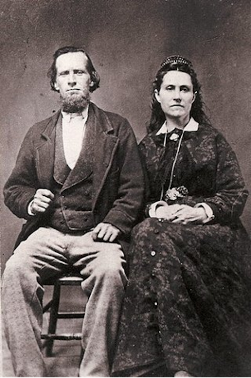 A sepia-toned portrait of a man and woman seated together, dressed in 19th-century clothing, with serious expressions.