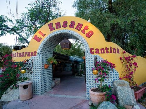 Colorful entrance archway of "El Encanto" restaurant and cantina, adorned with flowers and decorative tiles.