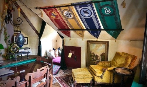 Cozy room with colorful house banners, a yellow armchair, and a desk, featuring a warm, inviting atmosphere.