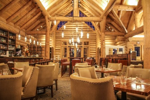 Cozy restaurant interior with wooden beams, warm lighting, and elegant seating arrangements.