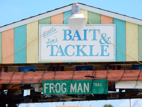 Colorful sign for "Little Jim's Bait & Tackle" with a green "Frog Man Trail" sign below it.