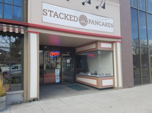 Exterior of Stacked Pancakes restaurant with an "Open" sign and a display window.