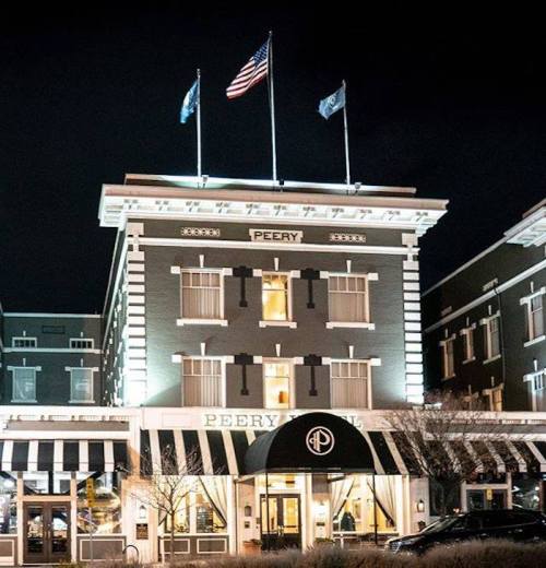 Historic Peery Hotel at night, featuring flags and elegant architecture, with a welcoming entrance.