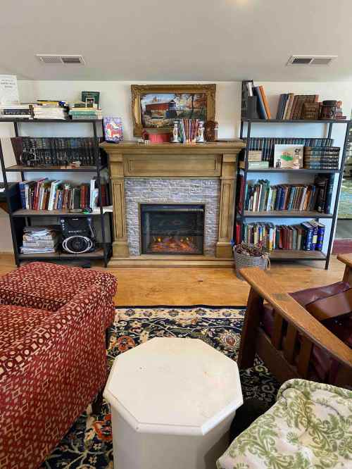 Cozy living room with a stone fireplace, bookshelves filled with books, and comfortable seating.