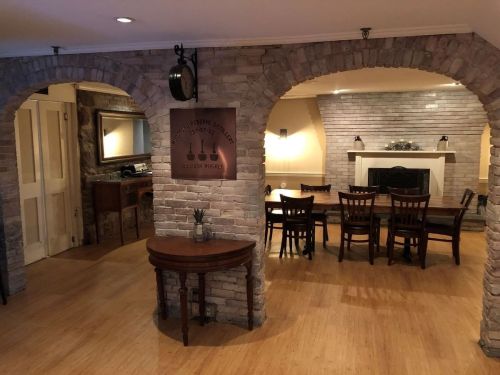 Interior view of a cozy room with stone arches, wooden furniture, and a dining area featuring a fireplace.