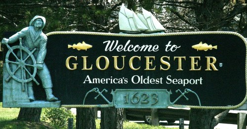 Welcome sign for Gloucester, America's oldest seaport, featuring a sailor and a ship design, established in 1623.