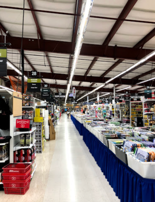 A wide aisle in a retail store, lined with shelves of products and a blue table displaying items.