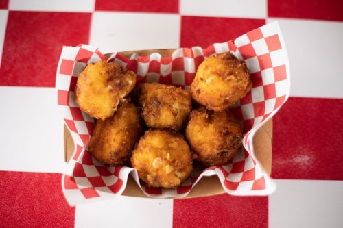 A basket of golden, crispy fried balls on a red and white checkered paper.