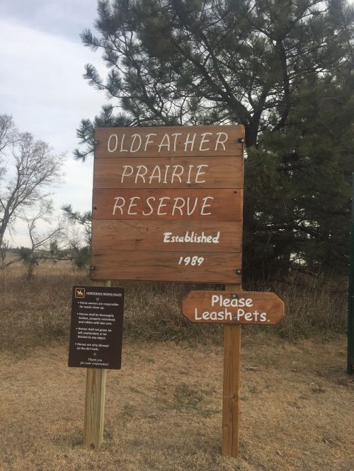 Wooden sign for Oldfather Prairie Reserve, established in 1989, with a note to please leash pets.