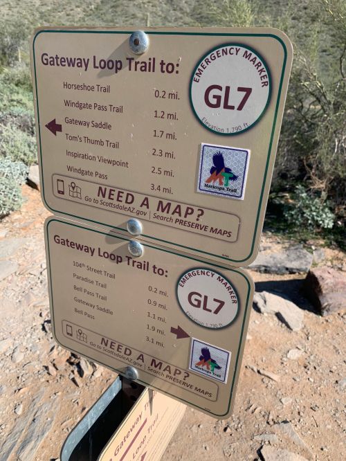Trail sign displaying directions and distances for the Gateway Loop Trail and nearby trails in a natural setting.