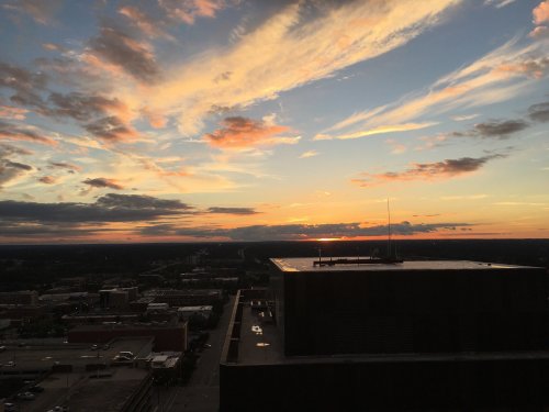 A vibrant sunset with colorful clouds over a city skyline, viewed from a high vantage point.