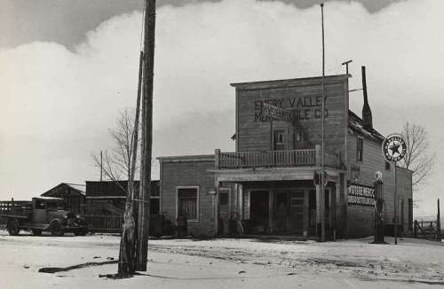 Historic black-and-white photo of a wooden building labeled "Every Valley Merchandise Co." with a vintage car parked outside.