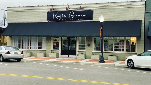 A boutique storefront with a black awning and large windows, featuring the sign "Katie Grace Boutique."
