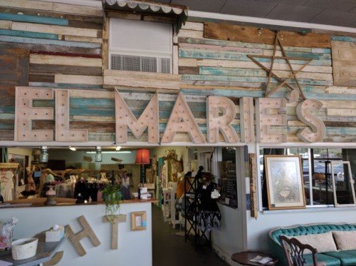 Interior of a shop named "El Marie's," featuring a rustic wooden wall and decorative elements.