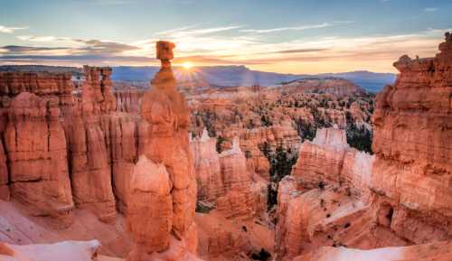 Sunrise over Bryce Canyon, highlighting unique rock formations and vibrant colors in the landscape.