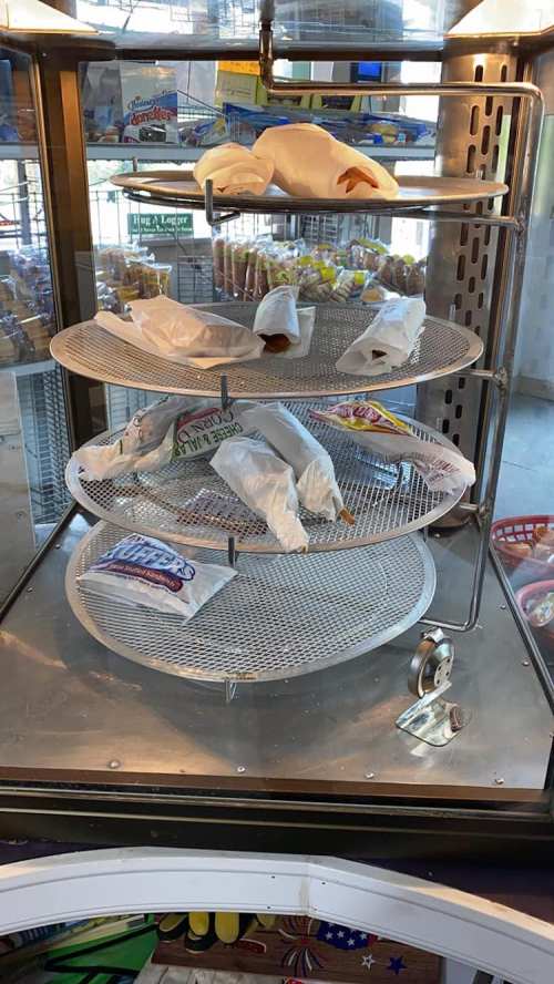 A display case with multiple tiers holding wrapped food items, set in a bright, well-lit environment.