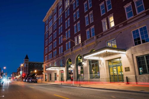 A historic brick building at night, featuring bright marquee lights and a bustling street scene.