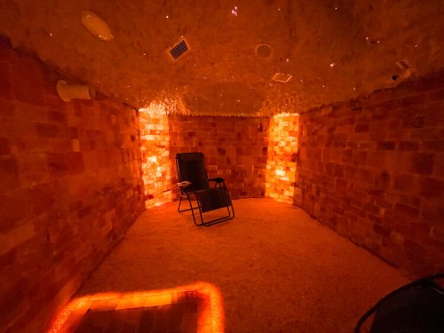 A cozy salt room with warm lighting, featuring a reclining chair and walls made of salt bricks.