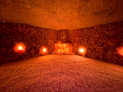 A cozy, dimly lit salt room with stone walls and glowing lamps, creating a warm and tranquil atmosphere.