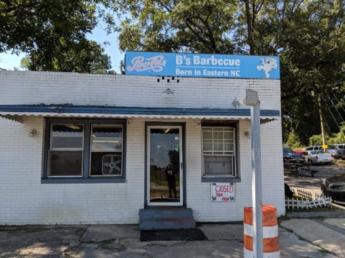 Exterior of B's Barbecue restaurant with a "CLOSED" sign, featuring a blue sign and white brick facade.