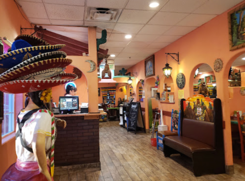 Colorful interior of a Mexican restaurant featuring vibrant decor, a statue, and a welcoming atmosphere.