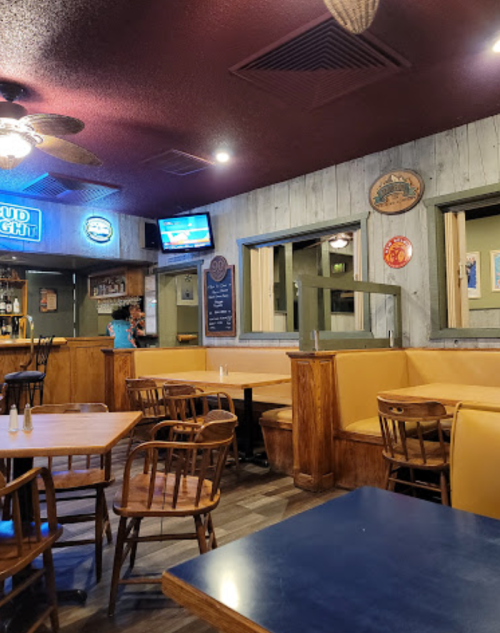 Cozy restaurant interior with wooden tables, yellow booths, and a TV on the wall, creating a warm atmosphere.