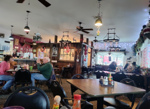 Cozy diner interior with patrons at tables, festive decorations, and warm lighting.