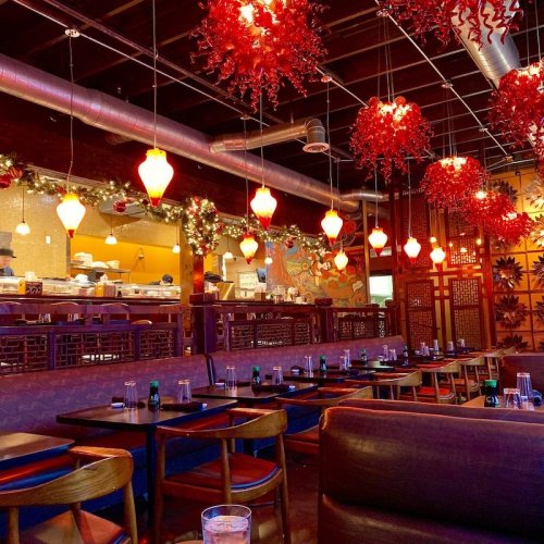 Cozy restaurant interior with red lanterns, festive decor, and wooden tables set for dining.