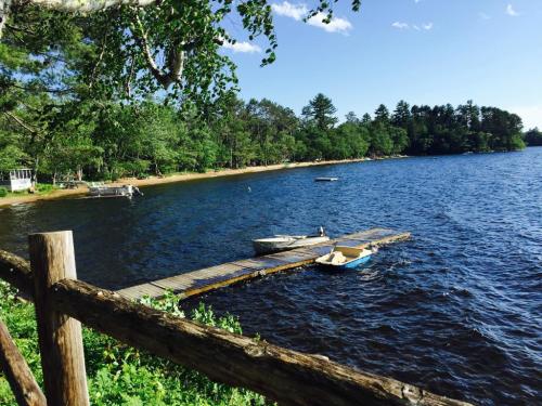 A serene lake scene with a wooden dock, boats, and lush greenery under a clear blue sky.