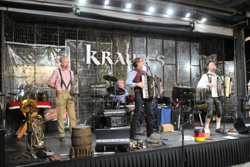 A lively band performs on stage with accordions, drums, and brass instruments at Krause's venue.
