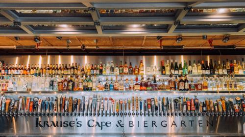 A vibrant bar with a wide selection of bottles and taps, featuring Krause's Cafe & Biergarten signage.