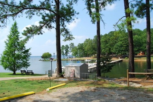 A serene lakeside view with docks, trees, and a clear blue sky, perfect for relaxation and outdoor activities.