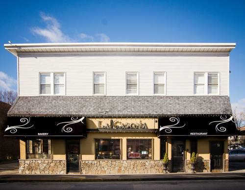 A two-story building with a bakery and restaurant, featuring decorative awnings and a clear blue sky above.