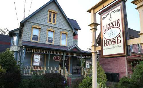 A colorful Victorian house with a sign reading "Lizzie Rose" in front, featuring a porch and decorative details.