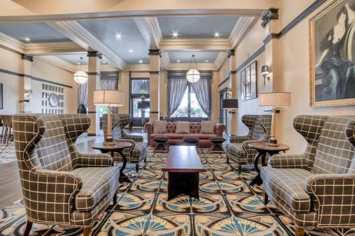 Elegant lobby with patterned carpet, plush seating, and stylish decor, featuring large windows and soft lighting.