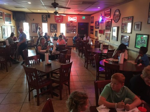 A busy restaurant interior with diners at tables, colorful wall decor, and a warm, inviting atmosphere.
