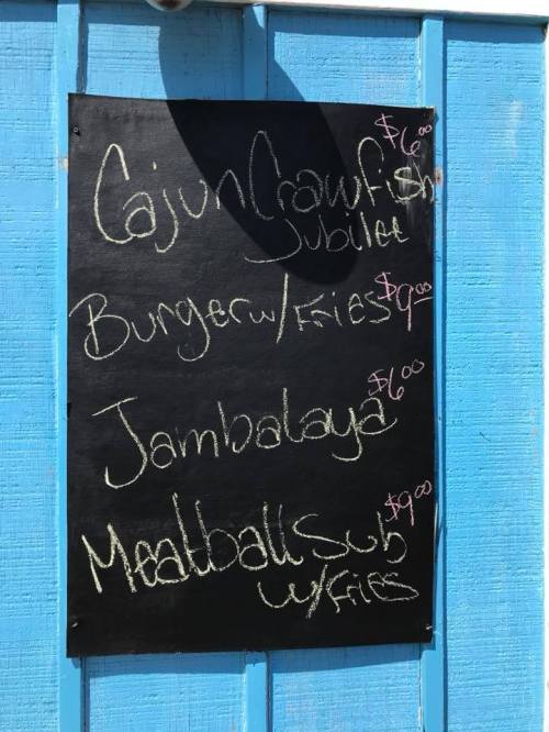 Menu board with items: Cajun Crawfish Jubilee $4, Burger w/ Fries $9, Jambalaya $6, Meatball Sub w/ Fries $7.