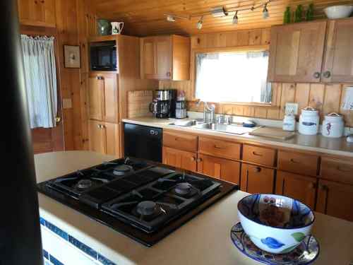 Cozy wooden kitchen with a gas stove, coffee maker, and natural light from a window.