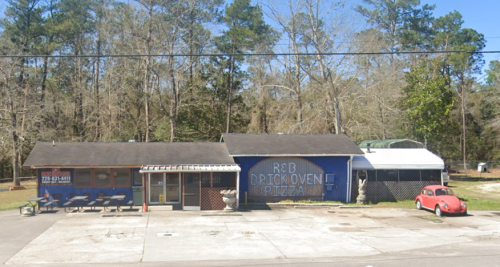 A blue building with a sign reading "R & B Brick Oven Pizza," surrounded by trees and featuring outdoor seating.