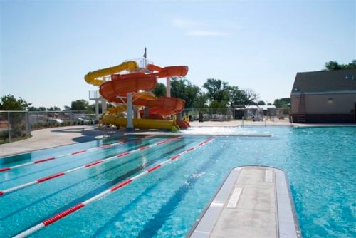 A sunny pool area featuring colorful water slides and a clear blue swimming pool with lane markings.
