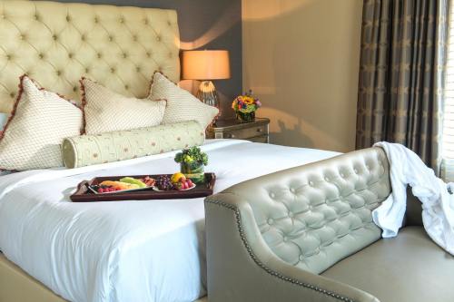 A cozy hotel room featuring a large bed with decorative pillows, a tray of fruit, and a stylish sofa.