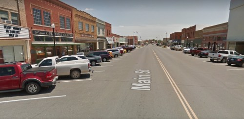 A view of Main Street lined with parked cars and historic buildings on either side under a clear sky.