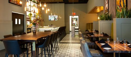 Modern restaurant interior featuring a long wooden table, elegant lighting, and stylish decor.