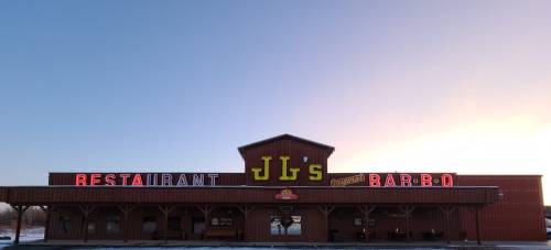 Exterior of JB's Restaurant and Original Bar-B-Q, featuring a wooden facade and colorful neon signage at sunset.
