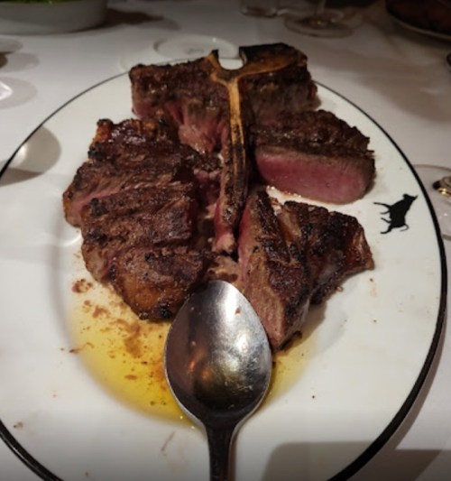 A beautifully cooked steak on a plate, sliced and served with a spoon beside it.