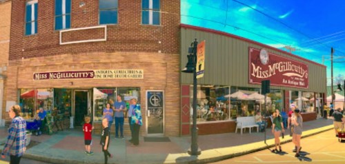 A vibrant street scene featuring shops, people, and outdoor seating in a charming small-town setting.